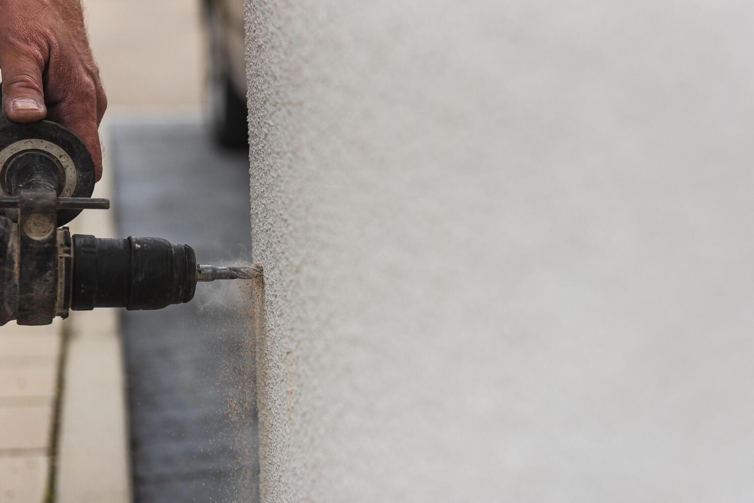 Handyman hand drilling a white wall